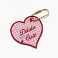 "Delulu But Cute embroidered pink gingham heart bag tag with gold hardware."